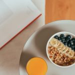 Top view of healthy breakfast with oatmeal, fresh fruit, and orange juice on a tray.