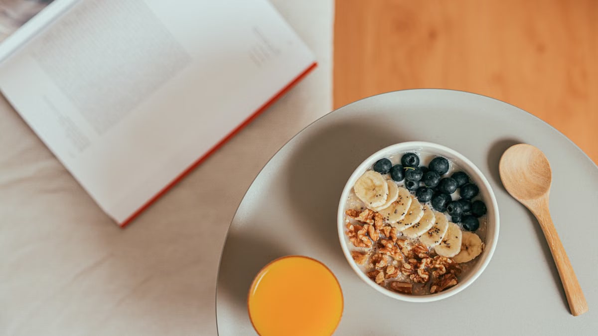 Top view of healthy breakfast with oatmeal, fresh fruit, and orange juice on a tray.